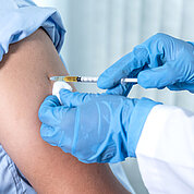 The doctor's hand holding a syringe and was about to vaccinate a patient in the clinic to prevent the spread of the virus