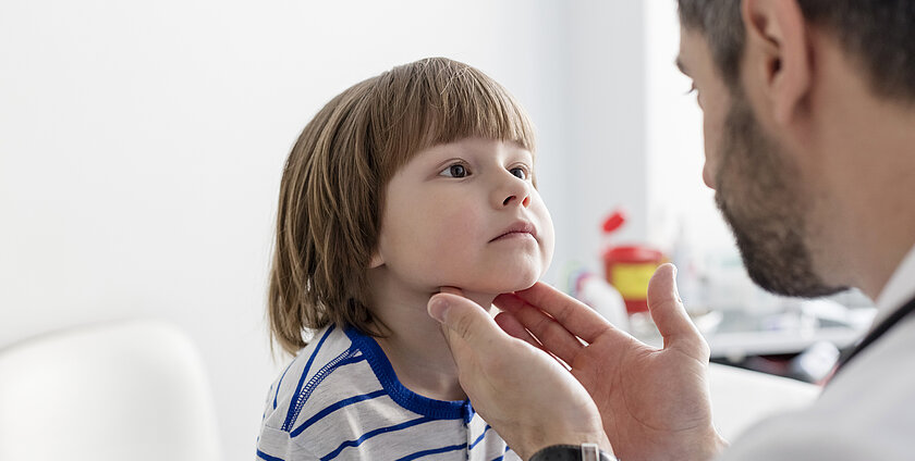 Doctor checking tonsils of patient at hospital