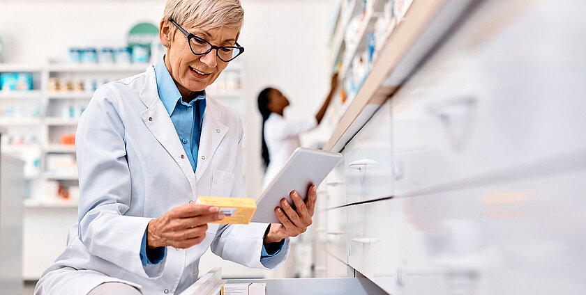Senior pharmacist using touchpad while going through inventory in a pharmacy.