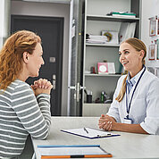 Young doctor is consulting joyful red-haired woman